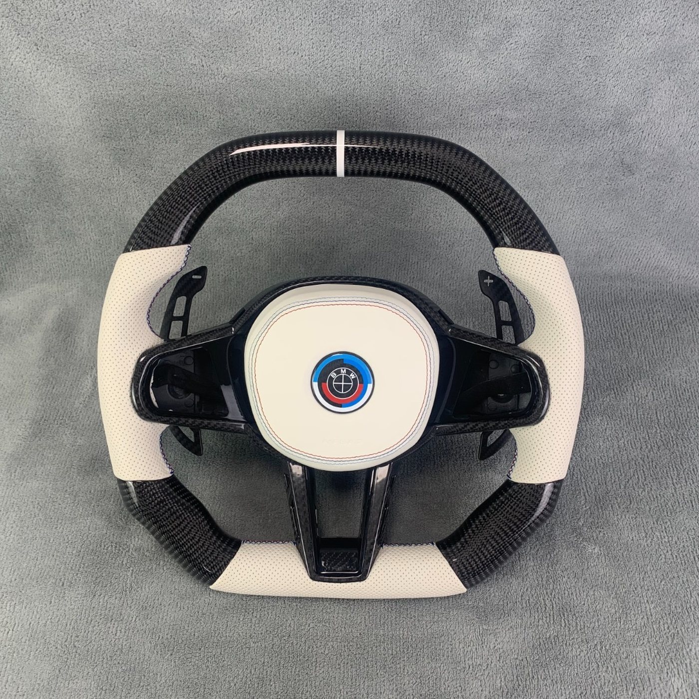 BMW G series custom gloss carbon fiber steering wheel in cream perforated leather with white centerline, carbon paddles and 50 year M badge by Miami Carbon Designs