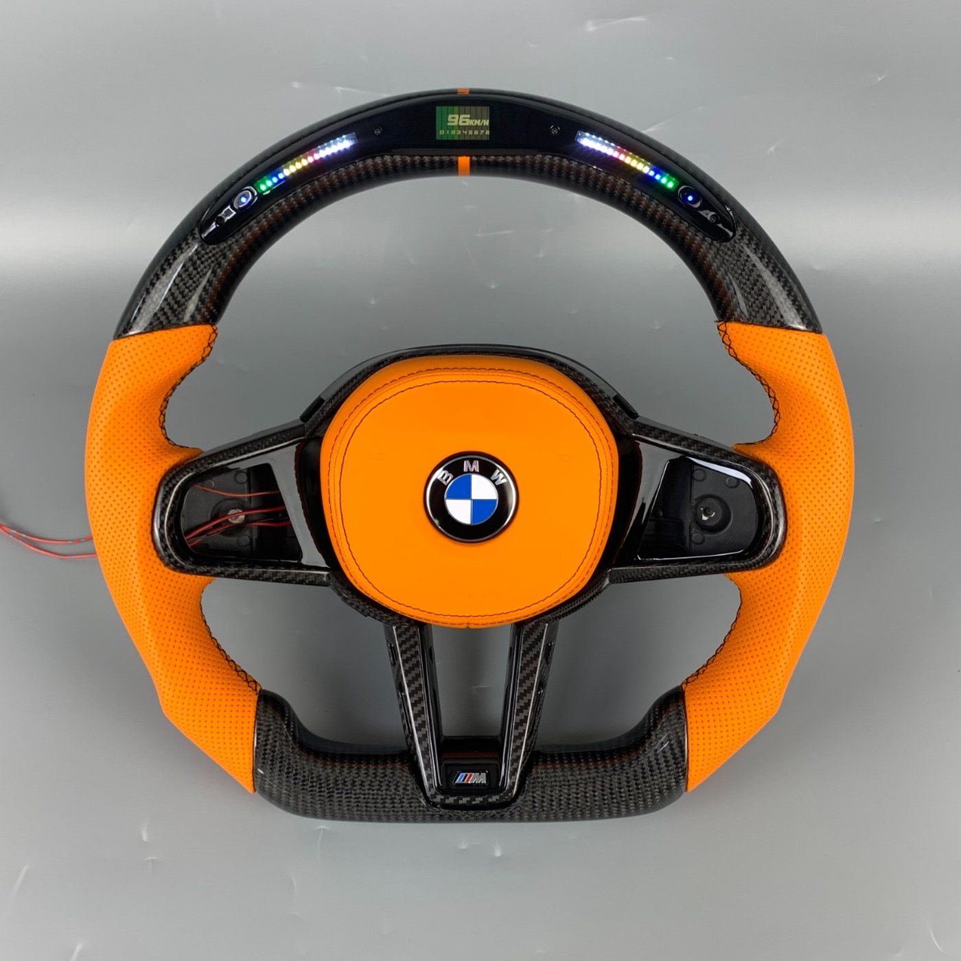 BMW G series custom gloss carbon fiber steering wheel in orange perforated leather with LED display and orange centerline by Miami Carbon Designs