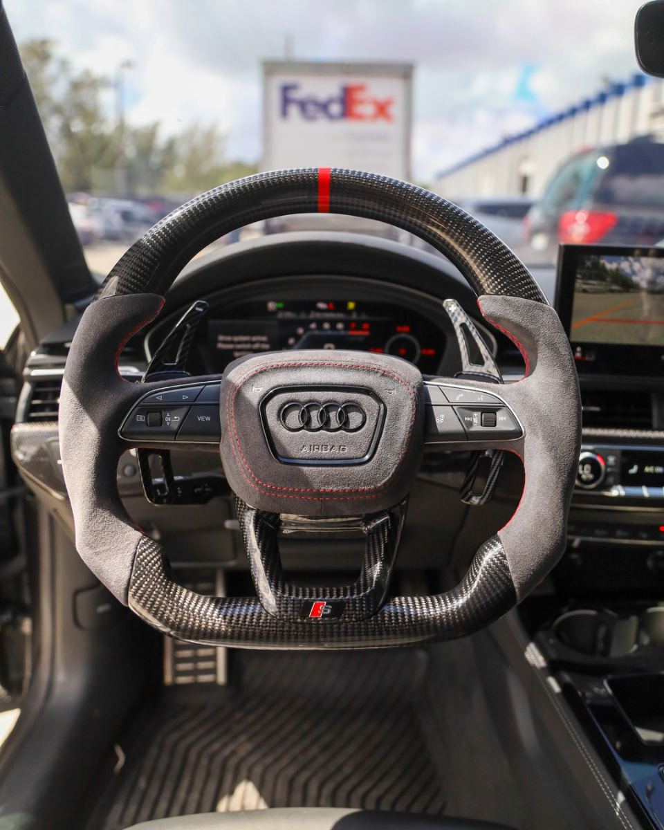 Custom carbon fiber steering wheel in gray Alcantara with red centerline installed in an Audi RS