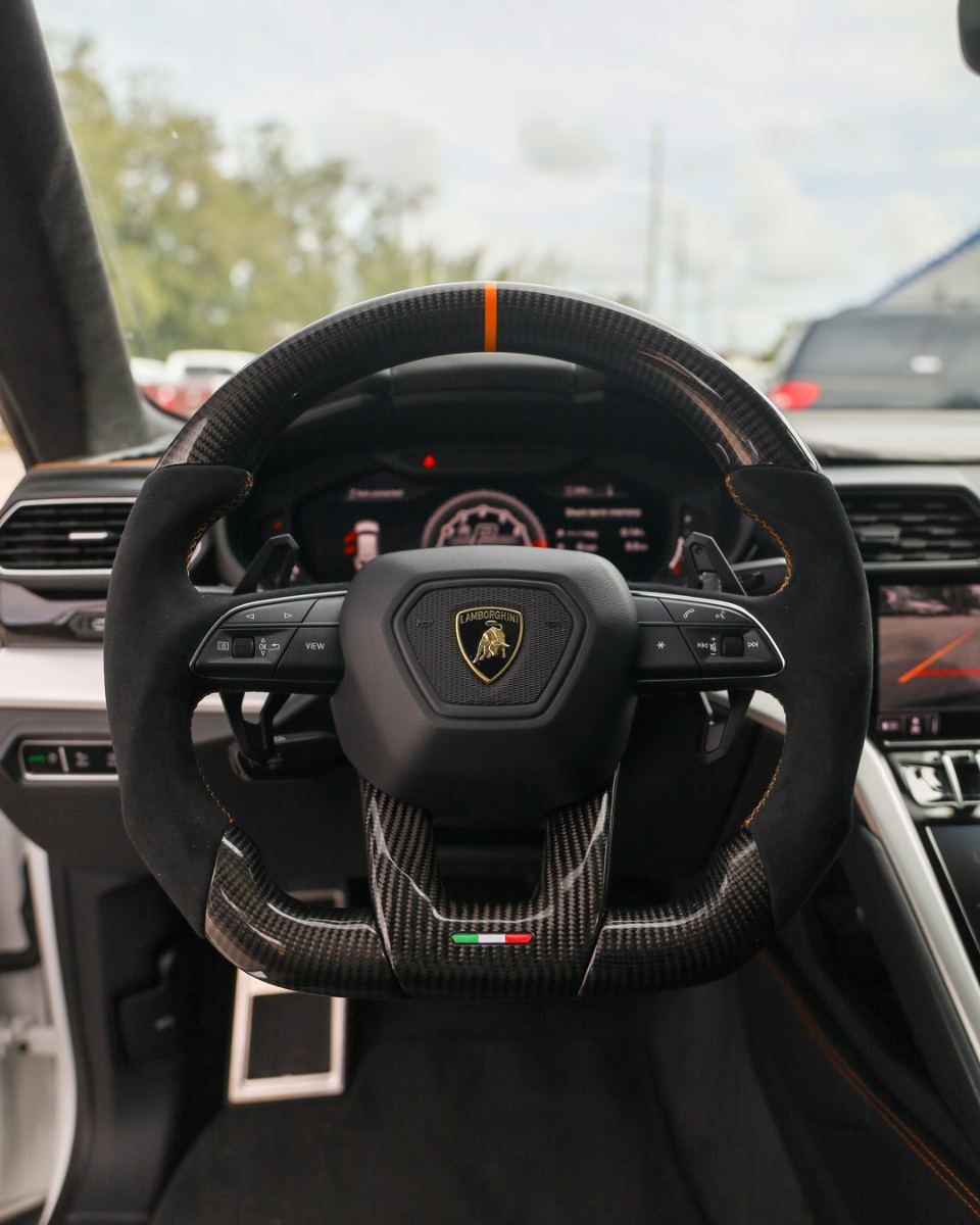 Custom carbon fiber steering wheel in black Alcantara with orange centerline installed in a Lamborghini