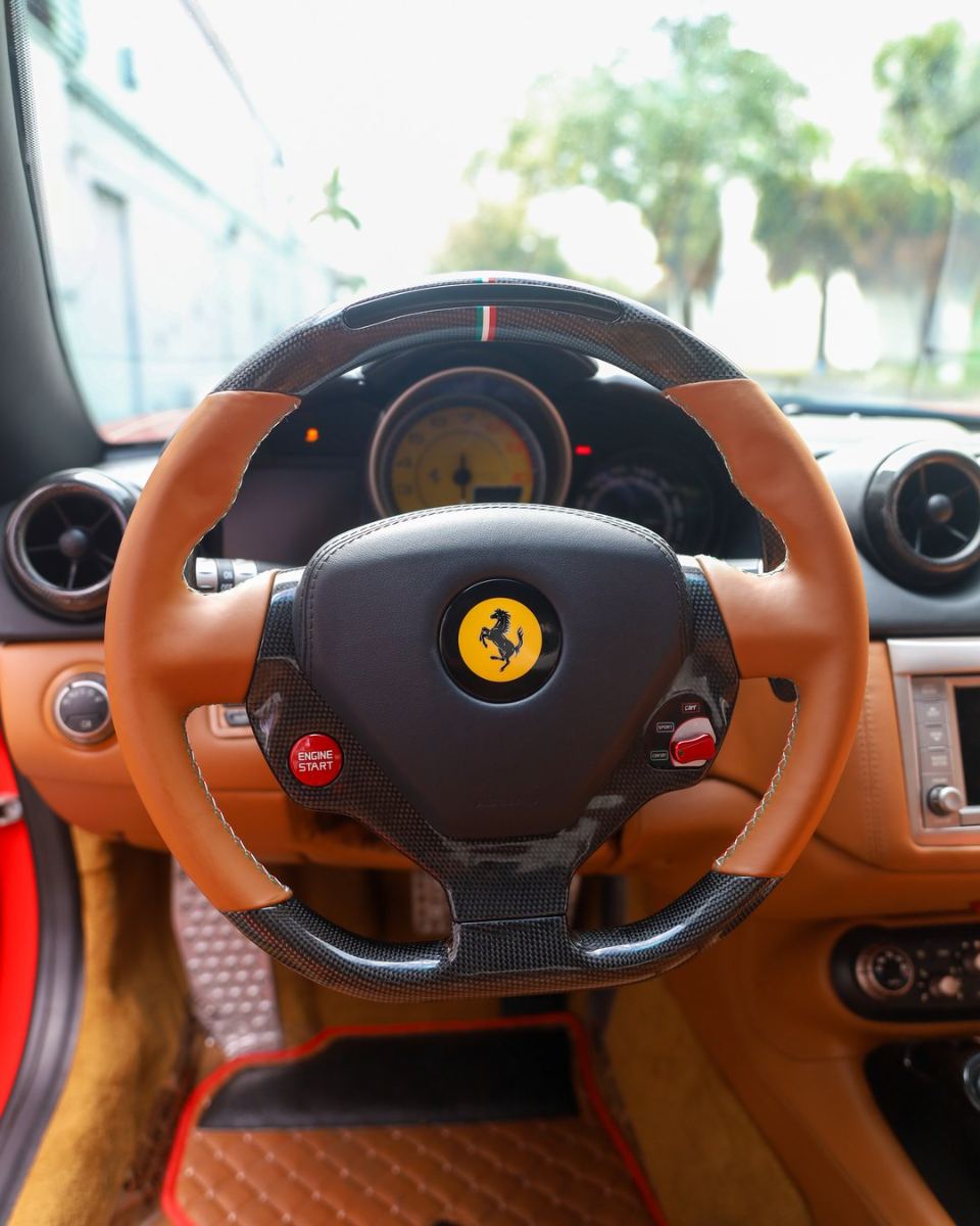 Custom carbon fiber steering wheel in tan leather with red centerline installed in a Ferrari