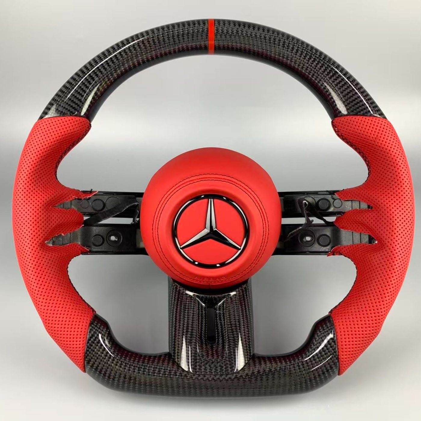 Mercedes 2024 custom gloss carbon fiber steering wheel in red perforated leather with red centerline and red airbag cover by Miami Carbon Designs