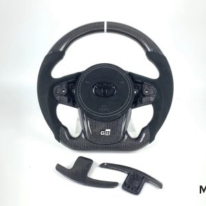 Toyota GR Supra custom carbon fiber steering wheel, black Alcantara, white stitching, white stripe, Alcantara airbag cover, carbon paddle shifters