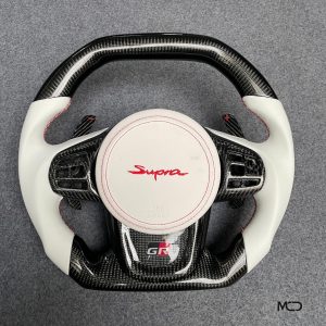 Toyota GR Supra custom carbon fiber steering wheel, white leather, red stitching, white airbag cover with red Supra logo, carbon paddle shifters